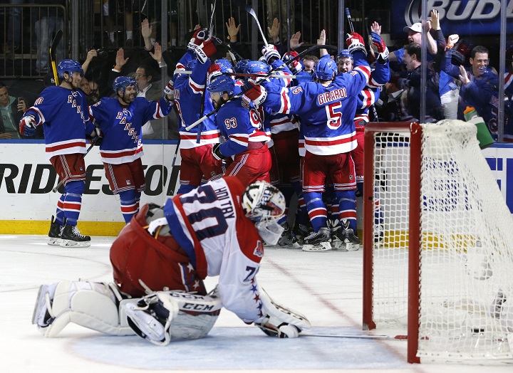 The New York Rangers celebrate the game winning goal by center Derek Stepan (21) against the Washington Capitals as Capitals goalie Braden Holtby looks at the puck in the net in overtime of Game 7 of the Eastern Conference semifinals during the NHL hockey Stanley Cup playoffs, Wednesday, May 13, 2015, in New York. The Rangers won 2-1. (AP Photo/Kathy Willens).