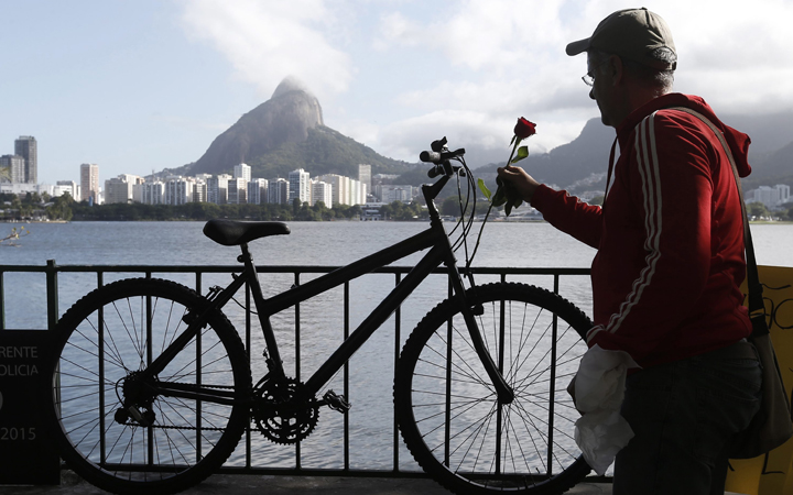 A man places a flower at the memorial for a cyclist who was stabbed to death in Rio de Janeiro, Brazil, Wednesday, May 20, 2015. Mayor Eduardo Paes has expressed confidence in the security arrangements for next year's Rio de Janeiro Olympics.