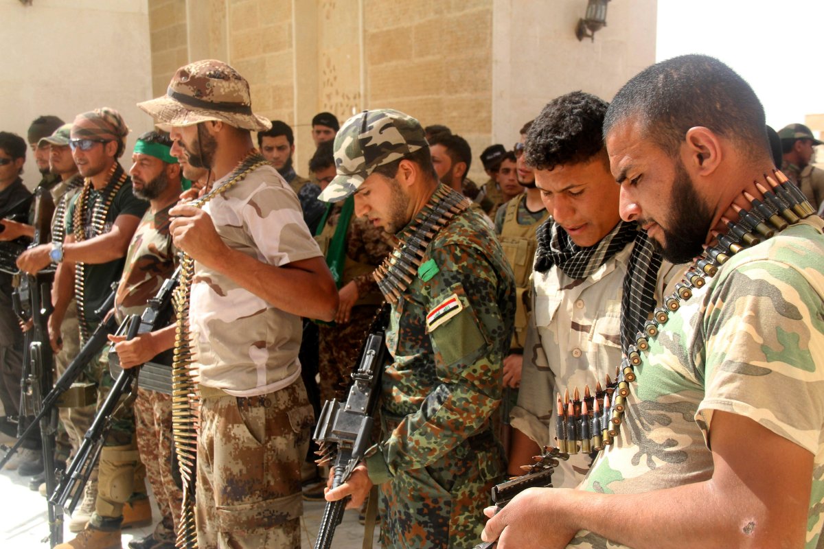 In this Thursday, May 21, 2015 photo, newly-arrived Iraqi Shiite militiamen check their weapons, in the predominately Sunni city of Nukhayb, southwest Iraq. 