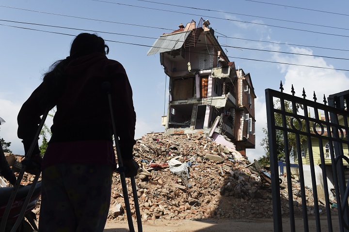 Nepalese resident Nomita Khadka leans on her crutches as she looks at the remains of her home in Kathmandu on May 1, 2015. 