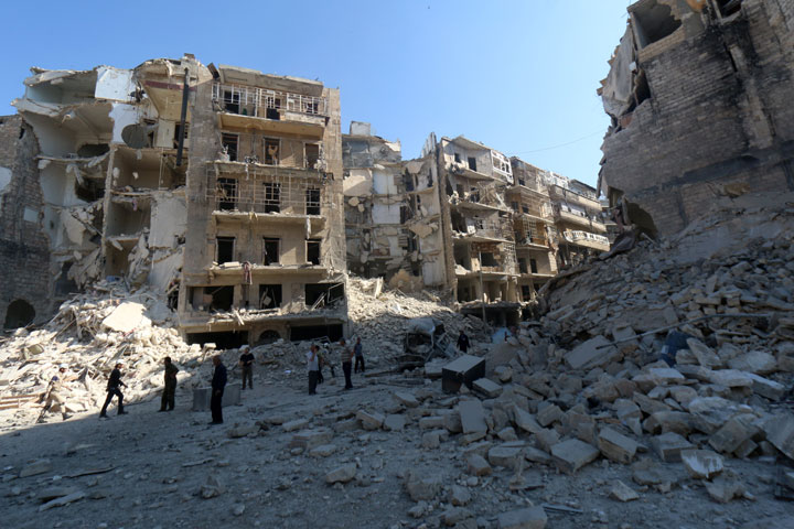 Syrians stand amidst the destruction in the eastern Shaar neighbourhood of the northern Syrian city of Aleppo on May 30, 2015.