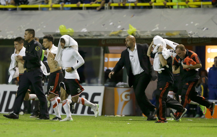 Argentina's River Plate players run away from the bench after a Copa Libertadores soccer match against Boca Juniors was suspended in Buenos Aires, Argentina, Friday, May 15, 2015. Conmebol delegate Roger Bello of Bolivia and referee Dario Herrera eventualy canceled the game after pepper spray was thrown from the stands towards River Plate players before the start of the second half of the game. 