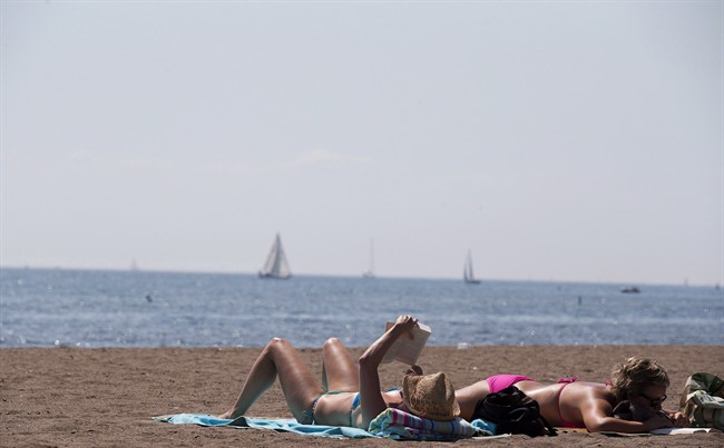 People read as they sunbathe on a warm summer day at Cherry Beach in Toronto. (Aug. 23, 2012).