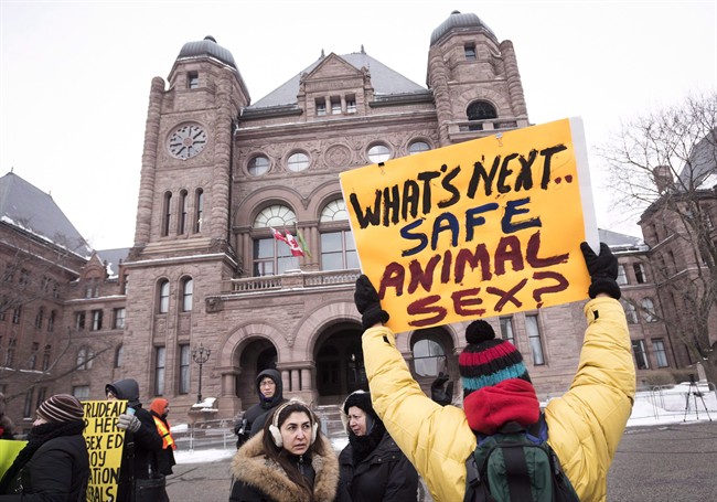 A demonstrator holds up a sign while gathering with others in front of Queen's Park to protest against Ontario's new sex education curriculum in Toronto on Tuesday, February 24, 2015.