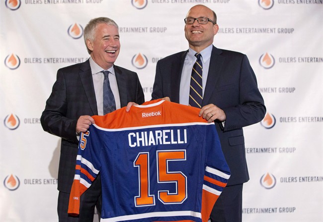 Edmonton Oilers CEO Bob Nicholson, left, and new President and General Manager Peter Chiarelli hold up an Oilers jersey with Chiarelli's name on it during a press conference in Edmonton, Alta., on Friday April 24, 2015.