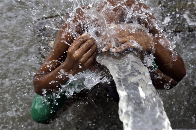 An Indian man bathes in water from a roadside tap in Kolkata, India, Sunday, May 31, 2015.
