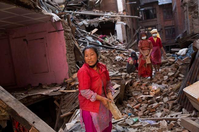 Nepalese women remove debris searching their belongings from their house that was destroyed a week ago during the earthquake in Bhaktapur, Nepal, Sunday, May 3, 2015. 