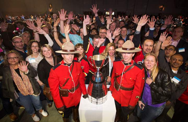 Shaw Communications employees celebrate with members of the RCMP and the Grey Cup during Shaw Communications/CFL partnership announcement in Calgary, Alberta, May 8, 2015.