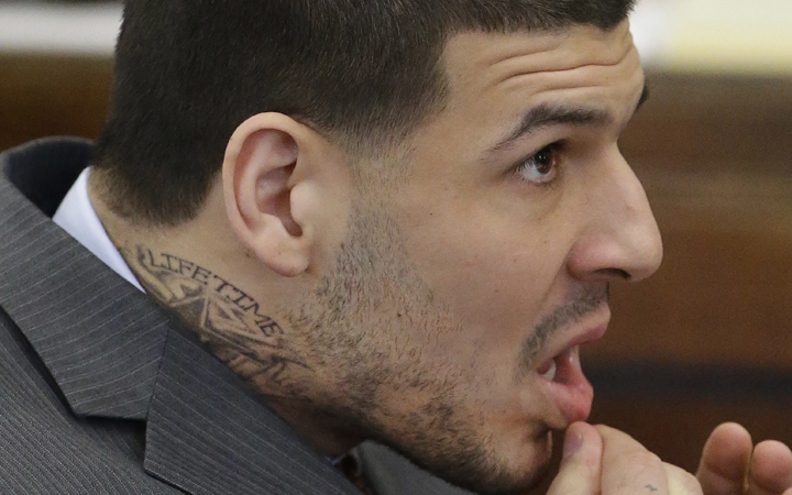 Sporting a new neck tattoo former New England Patriots NFL football player Aaron Hernandez sits at the defense table during his arraignment on a charge of trying to silence a witness in a double murder case against him by shooting the man in the face at Suffolk Superior Court, Thursday, May 21, 2015, in Boston. 