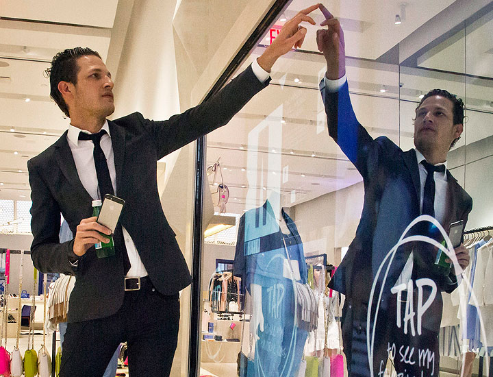 In this April 10, 2015 photo, Uri Minkoff, the company CEO and brother of designer Rebecca Minkoff, demonstrate an eight-foot by 11-foot-touch screen display where shoppers can flip through a catalog and indicate what items they want before entering a fitting room, at Rebecca Minkoff store in New York.