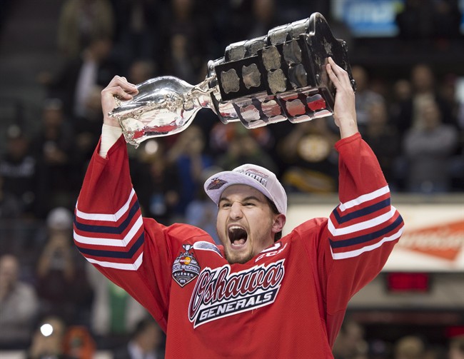 Oshawa Generals captain Josh Brown holds the Memorial Cup trophy over his head after his team won the tournament 2-1 in overtime against the Kelowna Rockets Sunday, May 31, 2015 at the Memorial Cup final in Quebec City. 