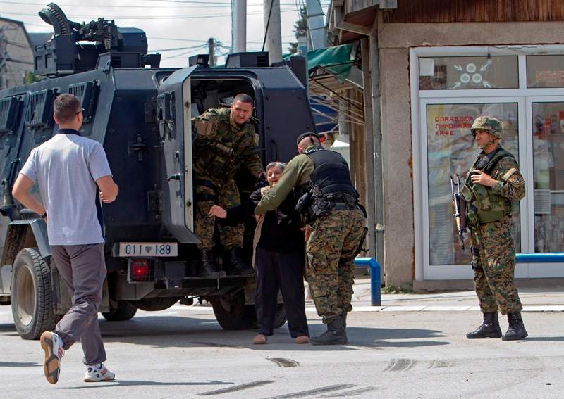 An elderly woman is evacuated safely as the fighting resumes for second day involving the police and an armed group, in northern Macedonian town of Kumanovo, on Sunday, May 10, 2015. Fighting between police forces and members of an armed group has continued for a second day in the northern Macedonian town of Kumanovo. 