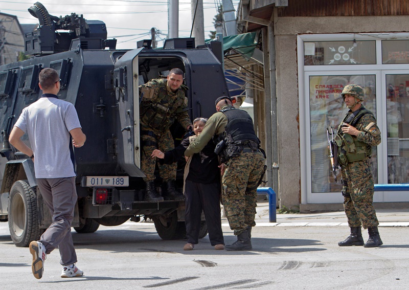 An elderly woman is evacuated safely as the fighting resumes for second day involving the police and an armed group, in northern Macedonian town of Kumanovo, on Sunday, May 10, 2015. Fighting between police forces and members of an armed group has continued for a second day in the northern Macedonian town of Kumanovo. 