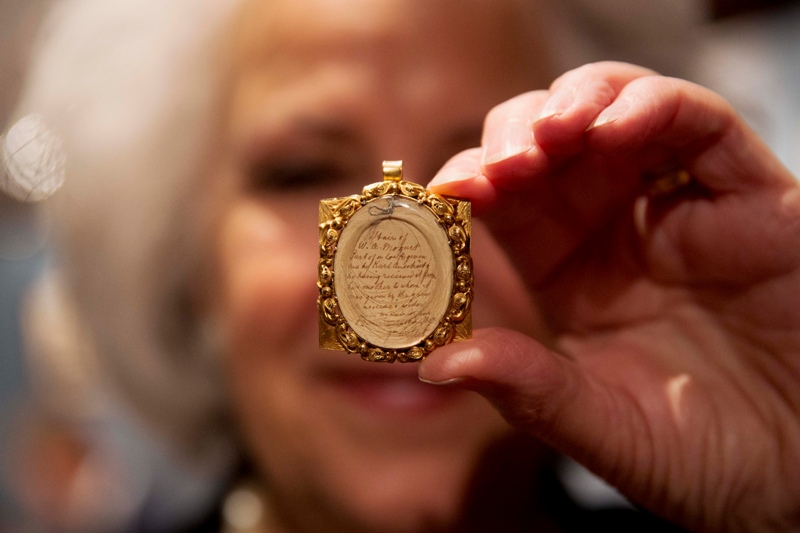 Gallery assistant Sandra Handley poses for photographs with a lock of Wolfgang Amadeus Mozart's hair, contained in a 19th-century gilt locket at the Sotheby's auction house in London, Tuesday, May 26, 2015. The lock of hair is estimated to fetch 10,000 to 12,000 pounds ($15,383 to $18,459, euro14,109 to 16,931) as part of the Music, Continental and Russian Books and Manuscripts auction on Thursday May 28 in London. 