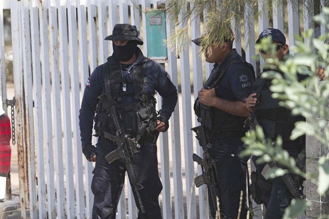 Mexican state police stand guard near the entrance of Rancho del Sol, near Vista Hermosa, Mexico, Friday, May 22, 2015.