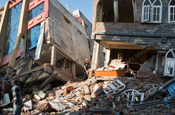 A rescue worker stands beside buildings that collapsed in an earthquake in Kathmandu, Nepal, Tuesday, May 12, 2015.