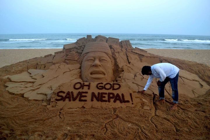 Indian sand artist Sudarsan Pattnaik gives the final touches to a sand sculpture representing the latest Nepal earthquake at Puri Sea beach on May 12, 2015.