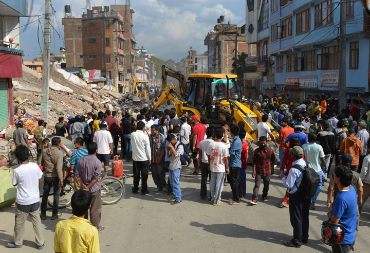 Rescue team officials and bystanders look for survivors in front of a collapsed house in Kathmandu May 12, 2015.