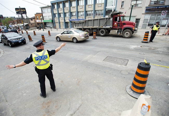 Off-duty City of Toronto police officers manage traffic in a construction zone in Toronto on Monday, May 11, 2015. 