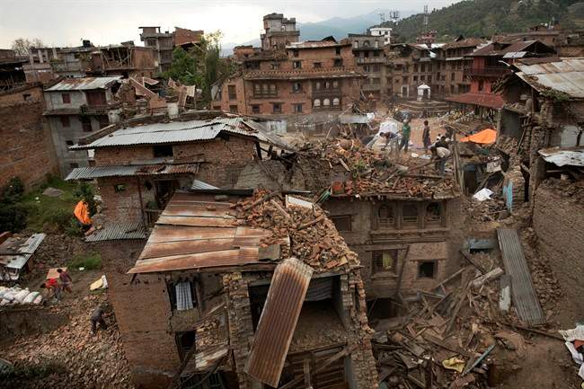 FILE - In this April 29, 2015 file photo, people clear the debris from damage caused by an earthquake in Sakhu, on the outskirts of Kathmandu, Nepal. 