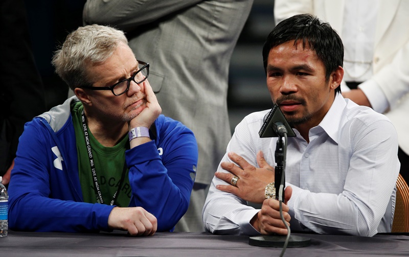 In this May 2, 2015 photo, trainer Freddie Roach listens to Manny Pacquiao  during a press conference.