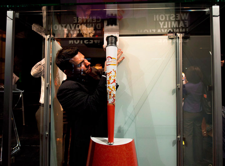 Staff place the official Pan Am torch back in its glass enclosure after unveiling the torch in Toronto on Monday, March 16, 2015.