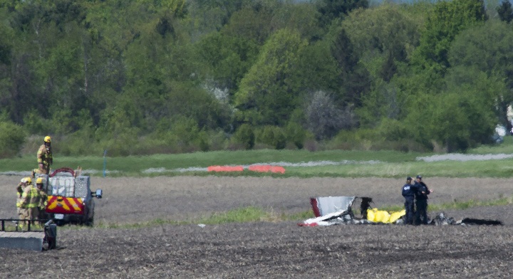 Police and emergency crews survey the scene near St-Lazare airport west of Montreal, Thursday, May 14, 2015, where a small plane crashed in a farmers field.