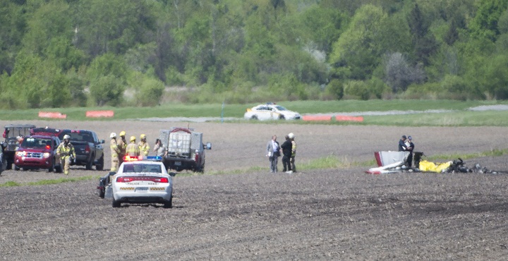 Police and emergency crews survey the scene near St-Lazare airport west of Montreal, Thursday, May 14, 2015, where a small plane crashed in a farmers field.