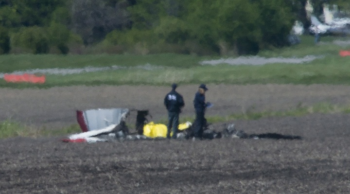 Police and emergency crews survey the scene near St-Lazare airport west of Montreal, Thursday, May 14, 2015, where a small plane crashed in a farmers field.