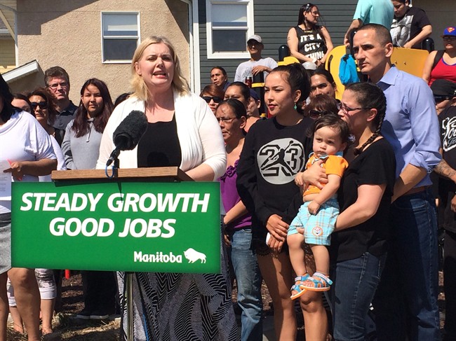 Manitoba Family Services Minister Kerri Irvin-Ross (center) and Jobs and The Economy Minister Kevin Chief (right, blue shirt) announce increased housing subsidies Friday, May 22, 2015 behind a sign bearing the government's Steady Growth, Good Jobs slogan. The slogan has been used in government ads that the opposition says amounts to partisan promotion for the NDP. THE CANADIAN PRESS/Steve Lambert.