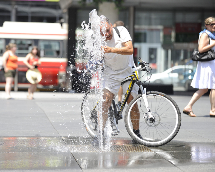 A bicyclist cooling off at the water fountain in Yonge-Dundas Square in Toronto.