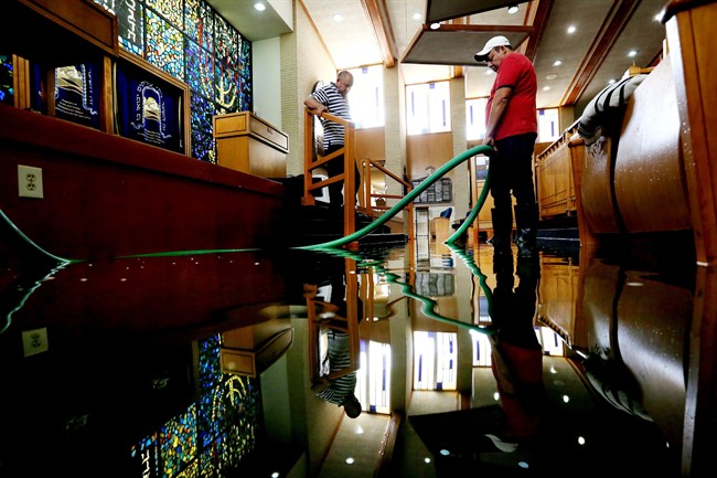 Wilber Albarenga, left, and Alfredo Chavez, pump water from the United Orthodox Synagogues of Houston, which suffered extensive damage by flooding from a recent storm Wednesday, May 27, 2015, in Houston. 
