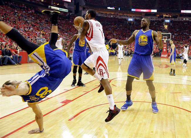Golden State Warriors guard Stephen Curry (30) topples over Houston Rockets forward Trevor Ariza (1) during the first half in Game 4 of the Western Conference finals of the NBA basketball playoffs as center Festus Ezeli (31) looks on, Monday, May 25, 2015, in Houston. 