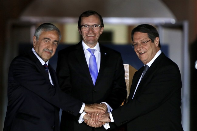 Cyprus' president Nicos Anastasiades, right, Turkish Cypriot leader Mustafa Akinci, left, and United Nations envoy Espen Barth Eide shake hands after a dinner at the Ledra Palace Hotel inside the UN controlled buffer zone that divides the Cypriot capital Nicosia, on Monday, May 11, 2015.