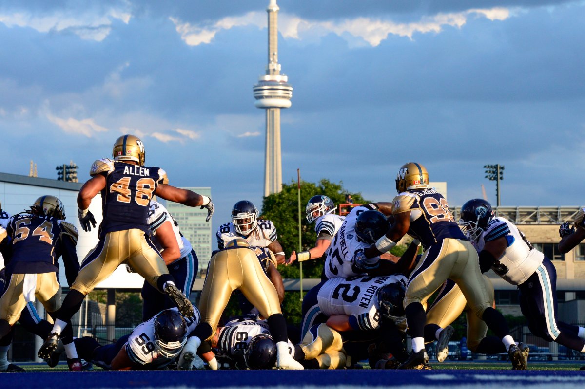 With the CN Tower and dark clouds in the background the Toronto Argonauts battle the Winnipeg Blue Bombers during first half CFL action at Varsity Stadium in Toronto on Tuesday June 9, 2015. 