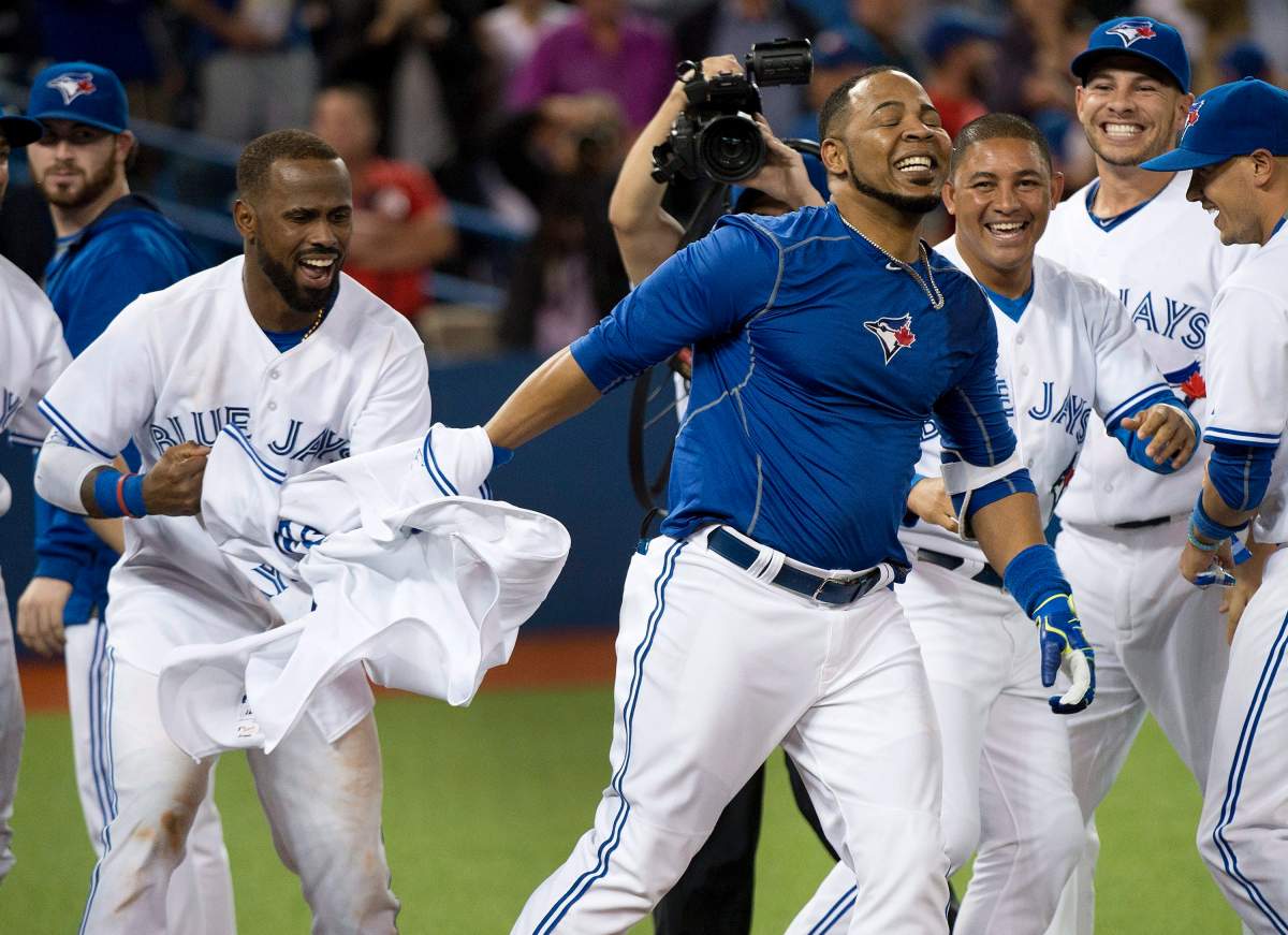 Toronto Blue Jays DH Edwin Enacarnacion, centre, gets his jersey ripped off after hitting a walk off two run home run to defeat the Miami Marlins during ninth inning interleague baseball action in Toronto on Tuesday, June 9, 2015. 