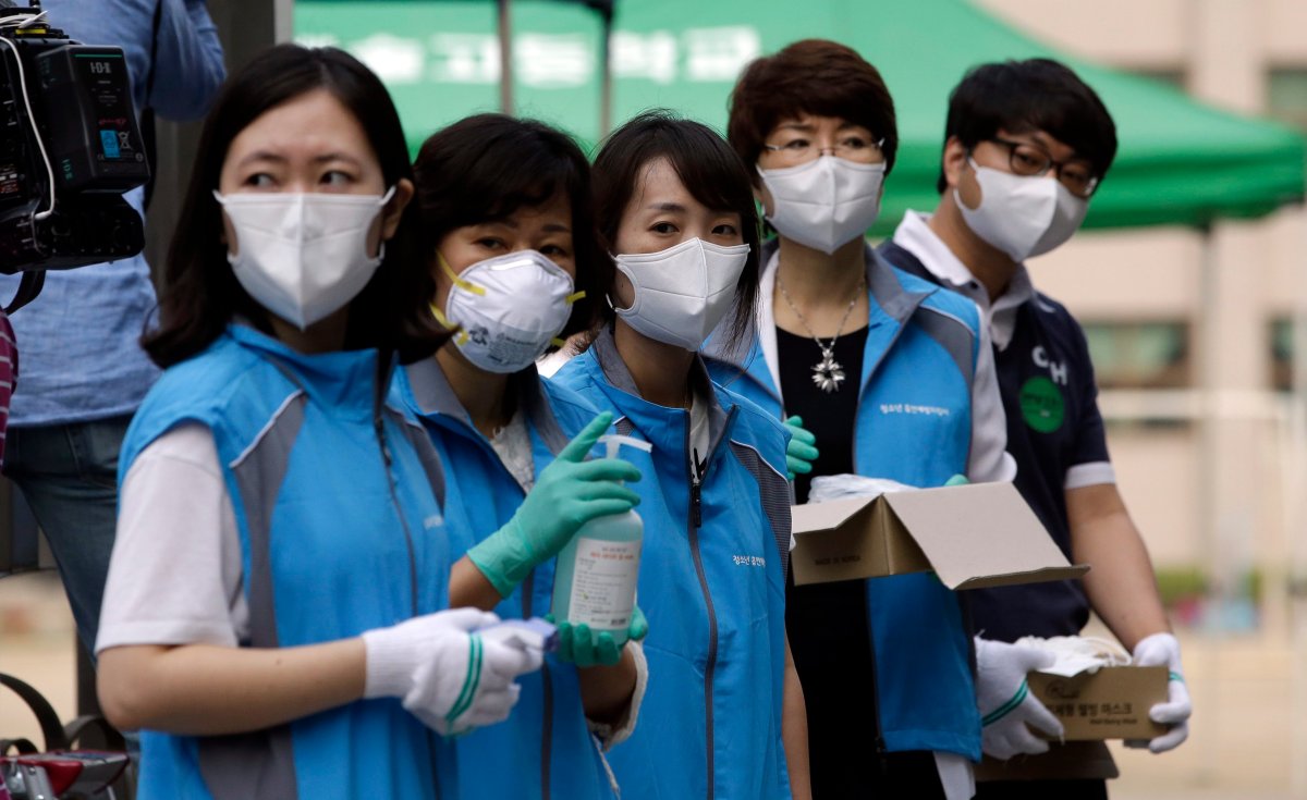 South Korean health workers from a community health center wearing masks as a precaution against MERS, Middle East Respiratory Syndrome, virus, wait to check examinees' temperature and to sanitzie their hands at a test site for a civil service examination in Seoul, South Korea, Saturday, June 13, 2015. 