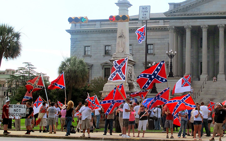 Supporters of keeping the Confederate battle flag flying at a Confederate monument at the South Carolina Statehouse wave flags during a rally in front of the statehouse in Columbia, S.C., on Saturday, June 27, 2015.