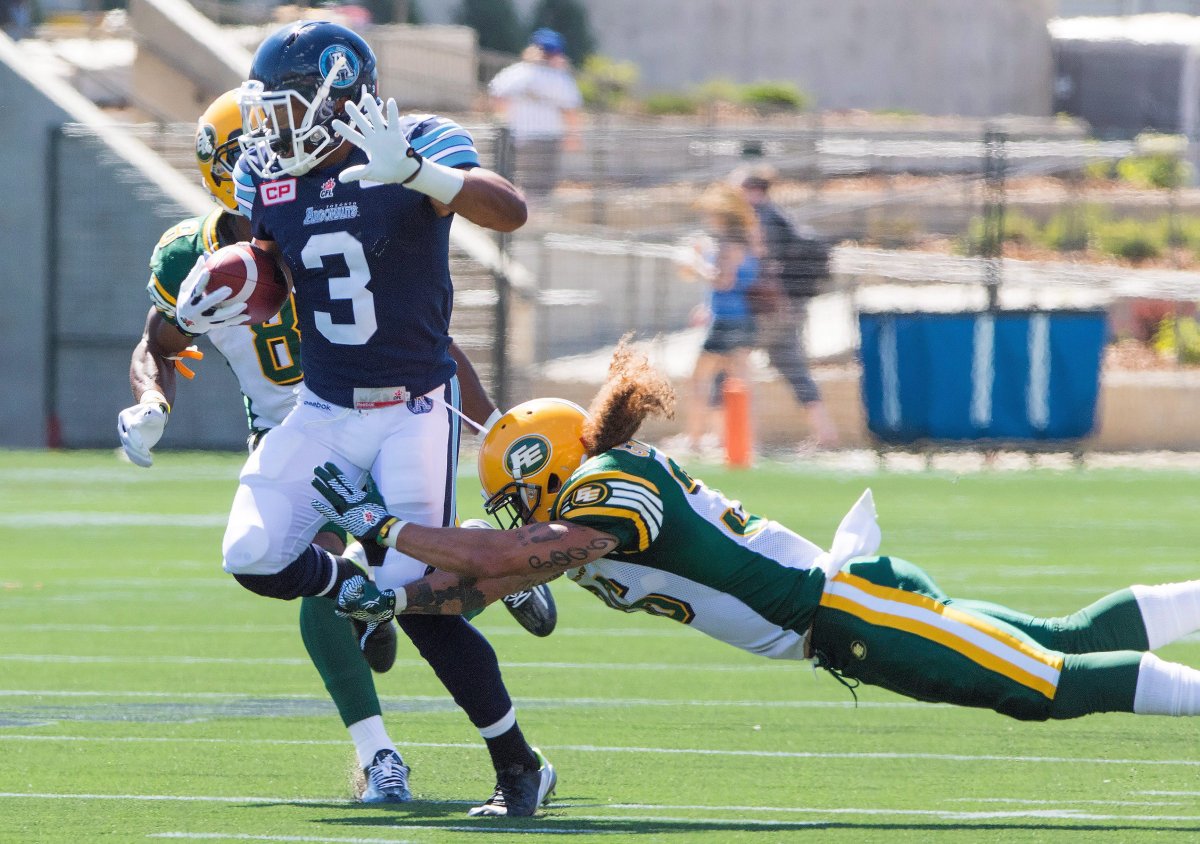 Toronto Argonauts' Brandon Whitaker (3) sidesteps a tackle from Edmonton Eskimos' Aaron Grymes (36) under pressure from Cauchy Muamba (8) during first half CFL football action in Fort McMurray, Alta., on Saturday, June 27, 2015. 