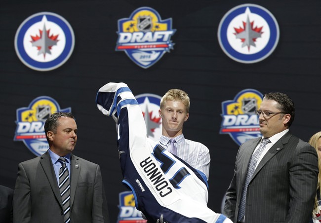 Kyle Connor puts on a Winnipeg Jets jersey after being chosen 17th overall during the first round of the 2015 NHL Entry Draft.