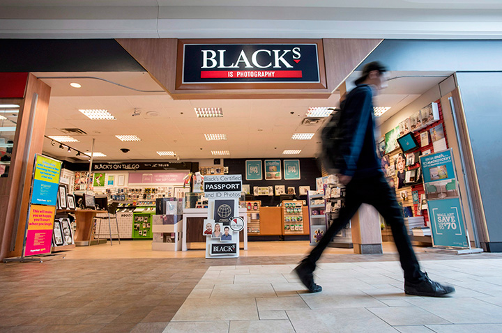 A man walks past a Blacks photo store in Ottawa on Tuesday, June 9, 2015. 