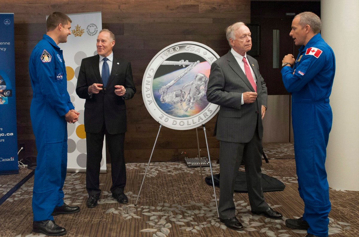 Canadian Space Agency (CSA) astronaut Jeremy Hansen, left, General (retired) Walter Natynczyk, President of the Canadian Space Agency, John Bell, director of the Royal Canadian Mint, and CSA astronaut David Saint-Jacques laugh and talk as they stand with the image of the new collector coin unveiled by the Royal Canadian Mint to celebrate the 25th anniversary of the Canadian Space Agency at the 65th International Astronautical Congress in Toronto on Tuesday, Sept. 30, 2014. 