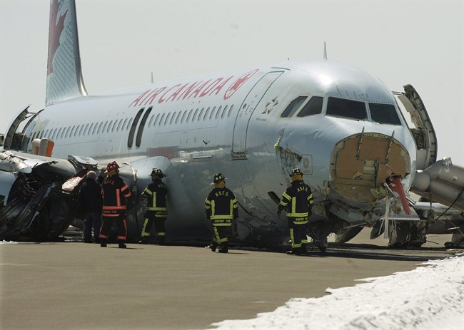 Transportation Safety Board investigators and airport firefighters work at the crash site of Air Canada AC624.