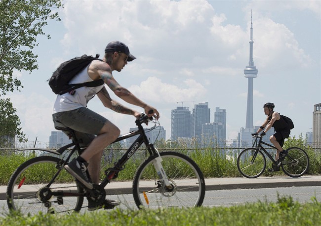 Cyclists ride past the skyline in Toronto on June 26, 2012.