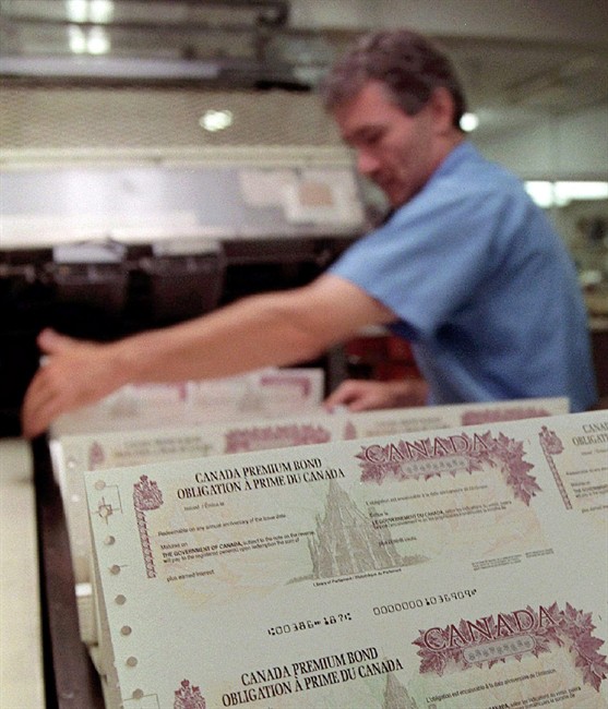 File photo of a worker stacks some of the new Canada Premium Bonds as they come off the presses at the Canada Bank Note Company in Ottawa, Sept.17, 1998.