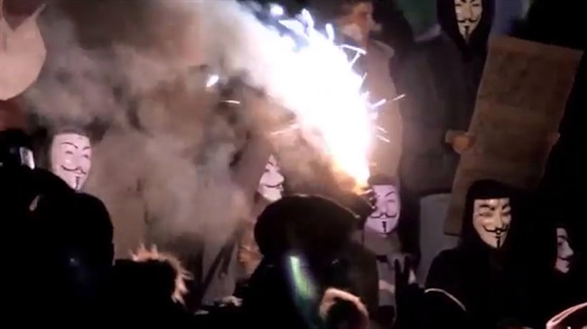 Protesters with Guy Fawkes masks are illuminated by flares in this screengrab from a YouTube video posted from an Anonymous-affiliated account.