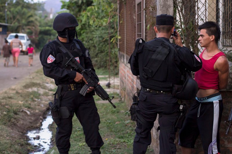 In this April 1, 2015 photo, a man is detained by police special forces in the town of San Juan Opico, El Salvador. 