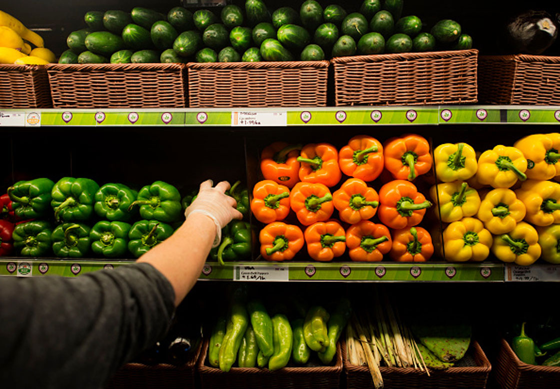 An employee stocks the shelves with fresh peppers in the produce section of a Whole Foods Market Inc.