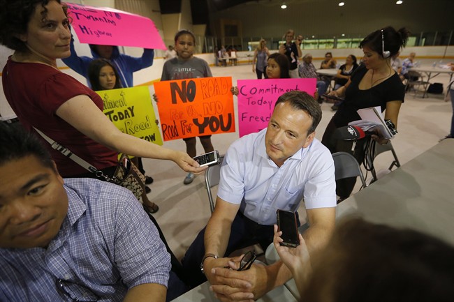 Federal natural resource minister Greg Rickford refuses to answer reporters questions as local children hold signs demanding a road in Shoal Lake 40 First Nation Thursday, June 25, 2015.