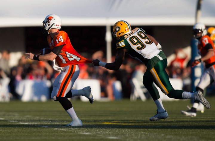 Edmonton Eskimos' Willie Jefferson, right, pulls on B.C. Lions' quarterback Travis Lulay's jersey during the first half of a pre-season CFL football game in Vancouver, B.C., on Friday June 19, 2015. 